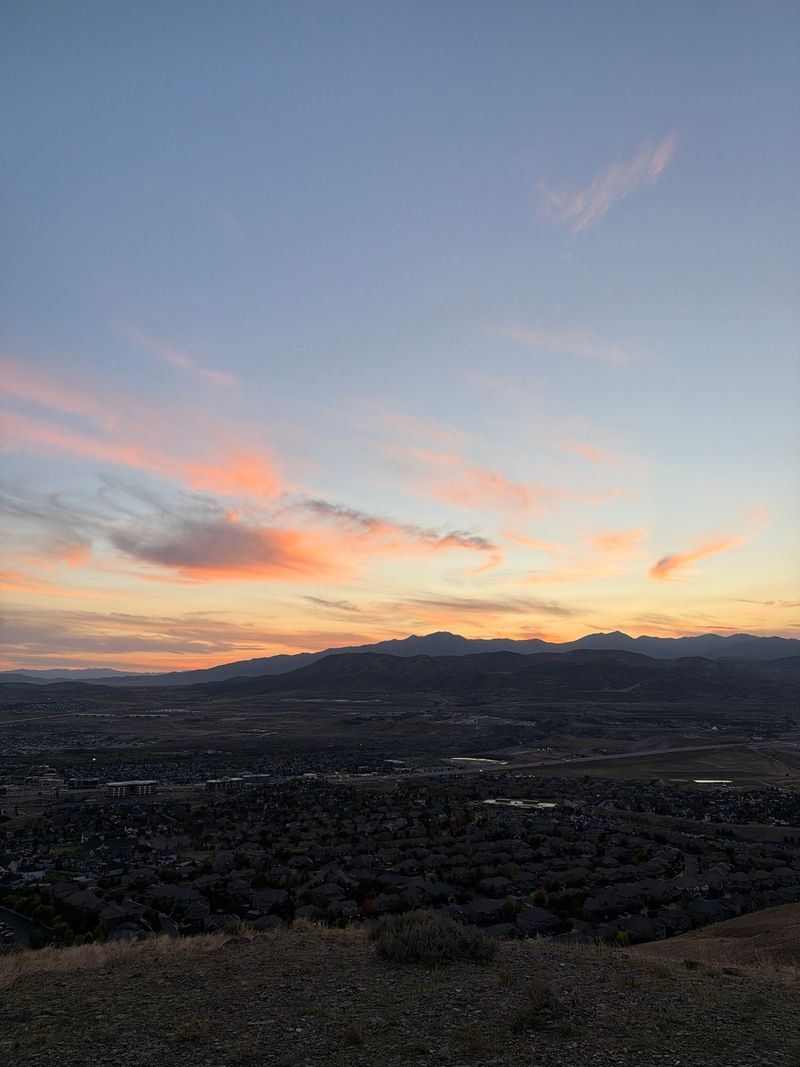 Pink clouds over a valley town and a far mountain ridge.